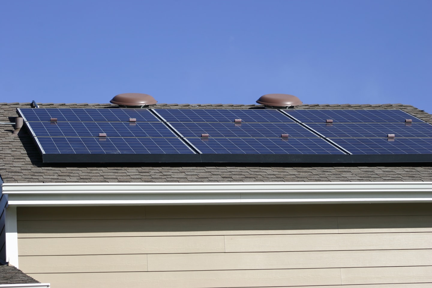 Donkerblauwe zonnepanelen op een beige woningdak.
